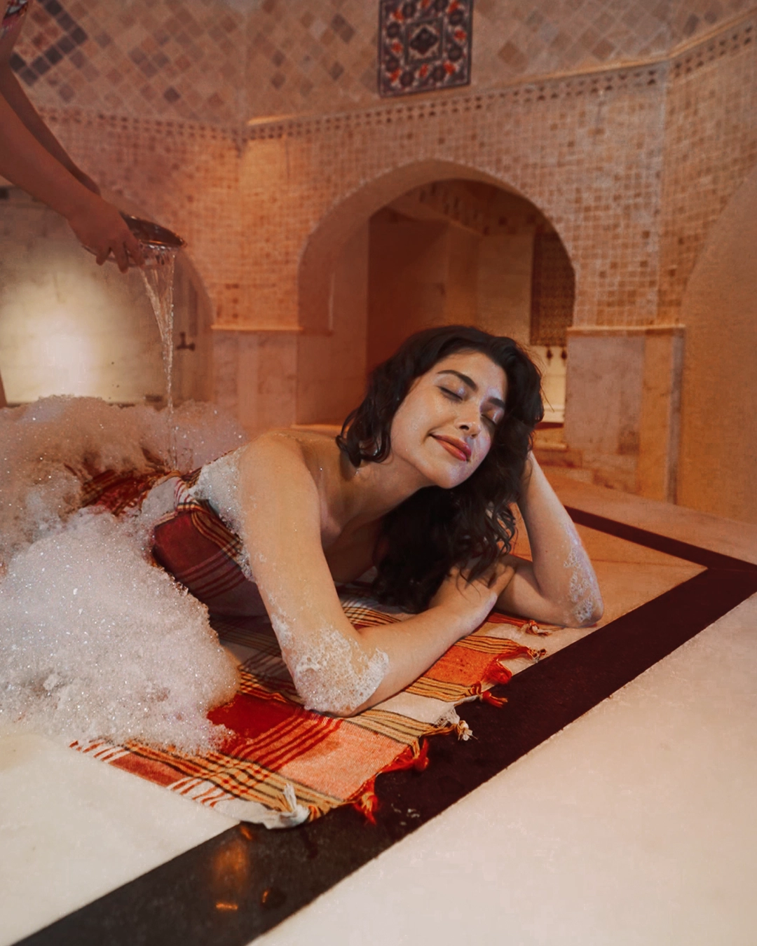 A guest resting under soft olive-oil foam