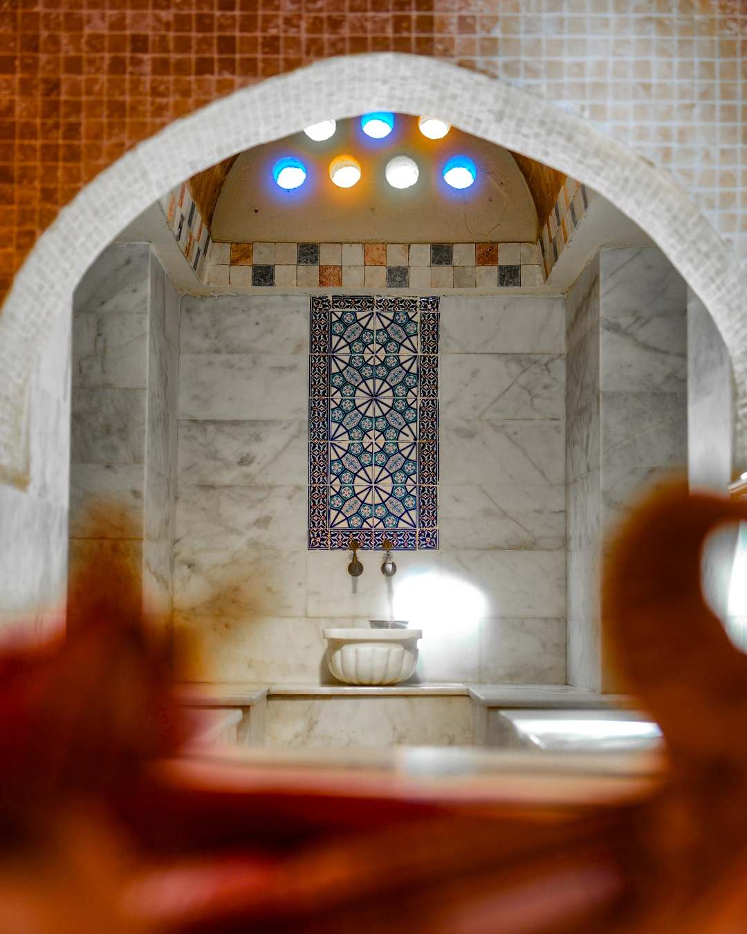 A decorated marble kurna alcove beneath coloured dome lights